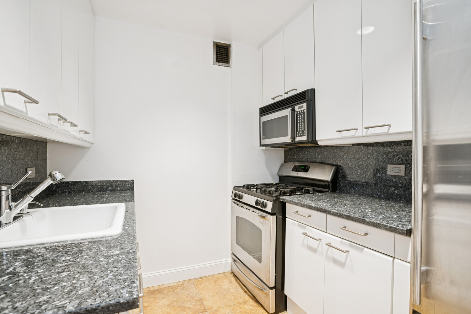 146 West 57th Street, Unit 34A Manhattan, NY 10019 - Photo 4 of 15 a kitchen with granite countertop a stove sink and microwave