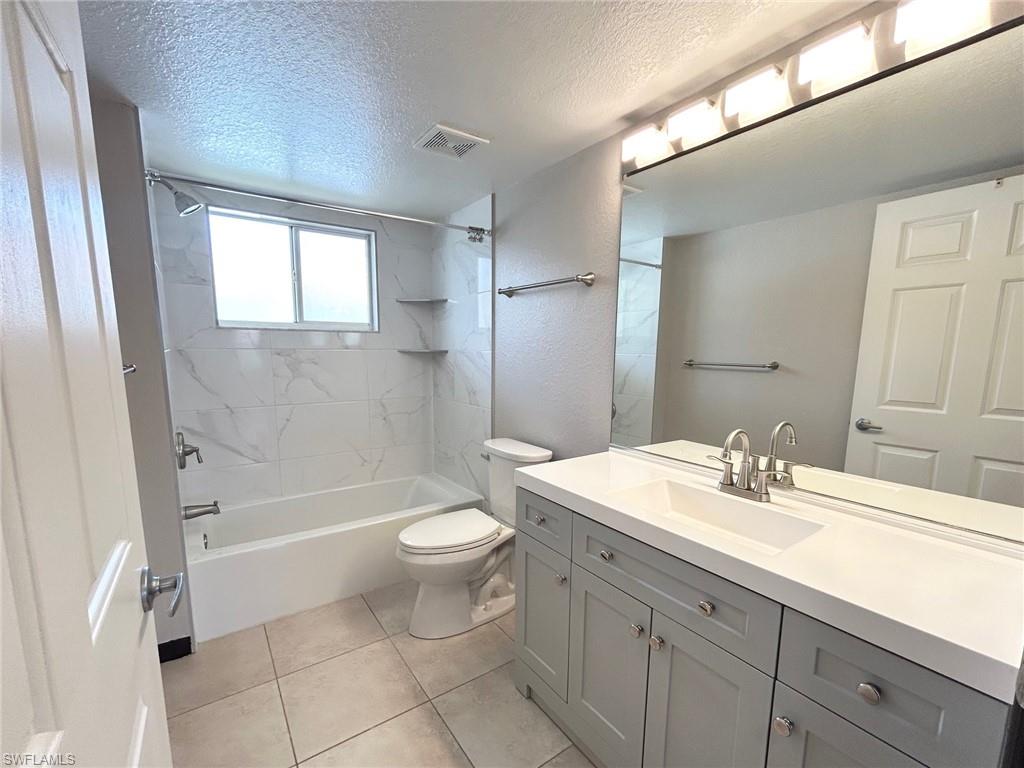 8284 Key Royal Circle, Unit 1323 Naples, FL 34119 - Photo 12 of 16 a bathroom with a sink a toilet a mirror and bathtub