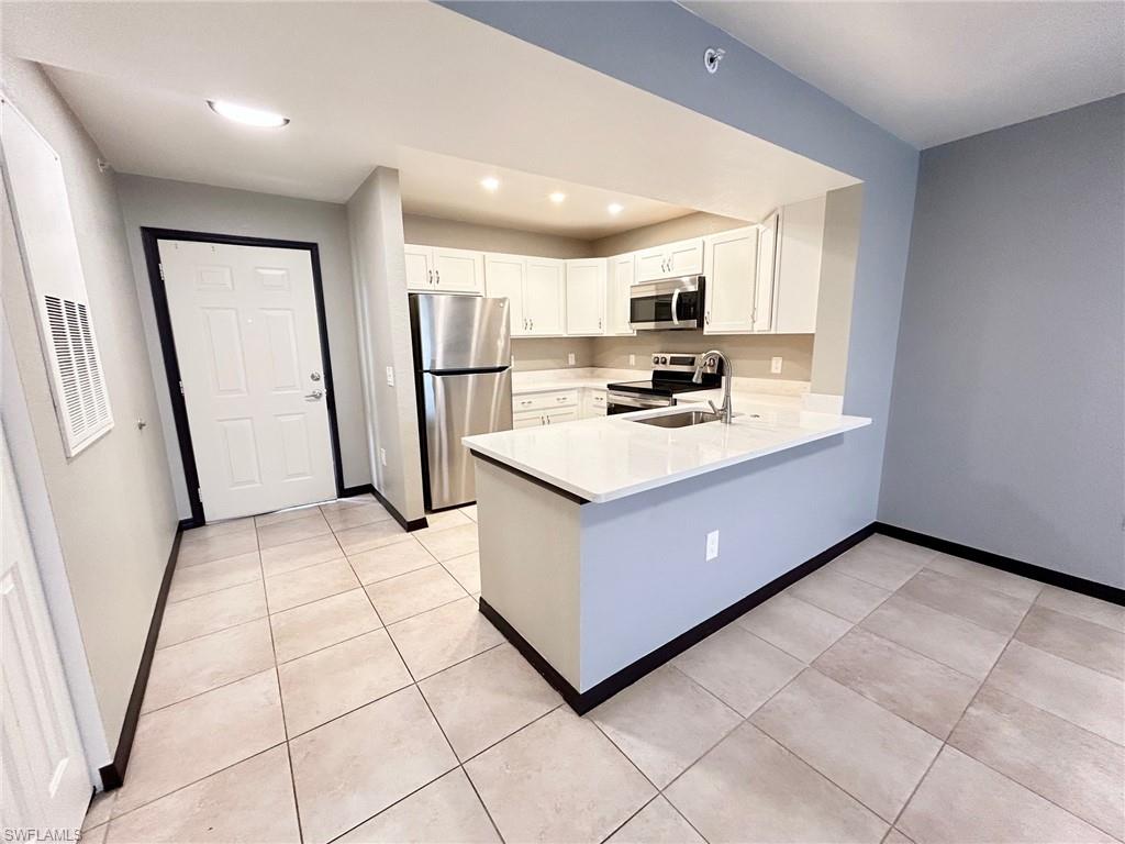 8284 Key Royal Circle, Unit 1323 Naples, FL 34119 - Photo 2 of 16 a kitchen with a sink a stove a refrigerator a microwave oven and a window