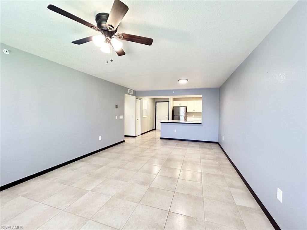 8284 Key Royal Circle, Unit 1323 Naples, FL 34119 - Photo 5 of 16 an empty room with windows and ceiling fan