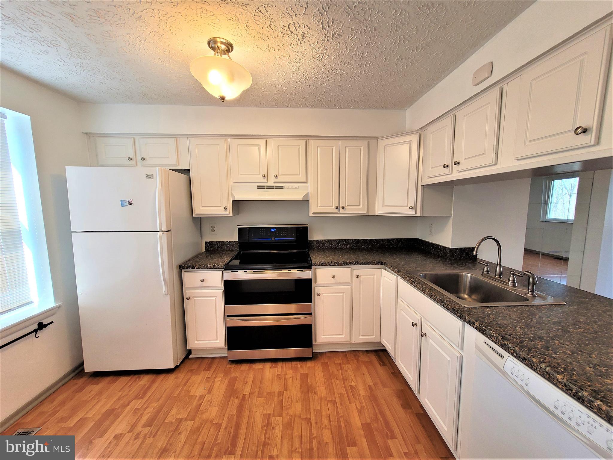 8072 Grandview Court Springfield, VA 22153 - Photo 11 of 32 a kitchen with granite countertop white cabinets and white appliances
