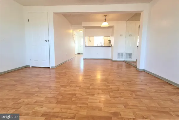 a view of a hallway with wooden floor and a bathroom