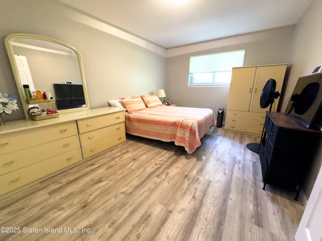 a spacious bedroom with a large bed and a flat tv screen on dresser