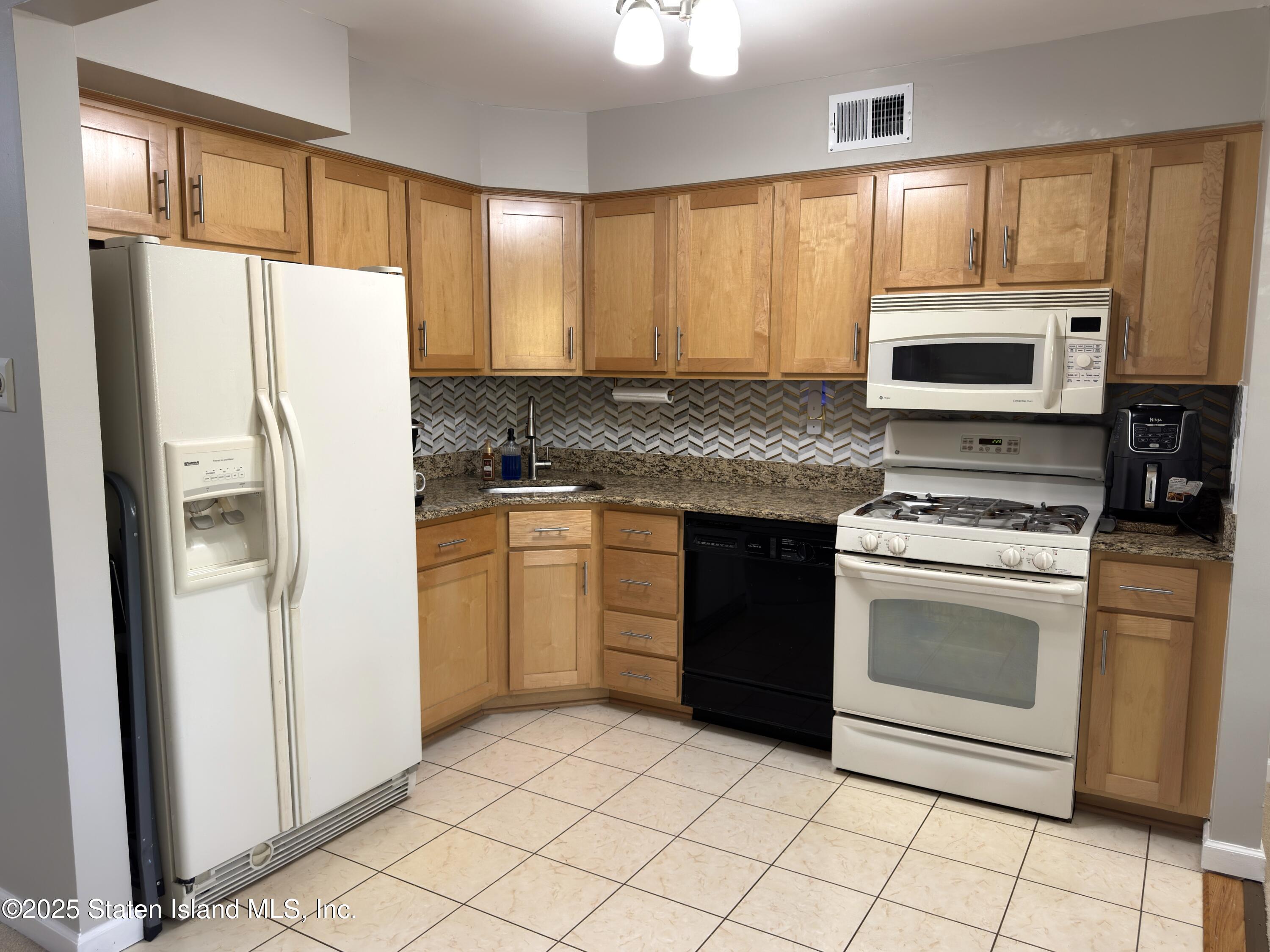 280 Rolling Hill Green Staten Island, NY 10312 - Photo 7 of 22 a kitchen with a stove a refrigerator and a microwave