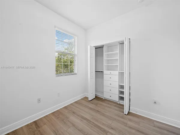 an empty room with wooden floor closet and windows
