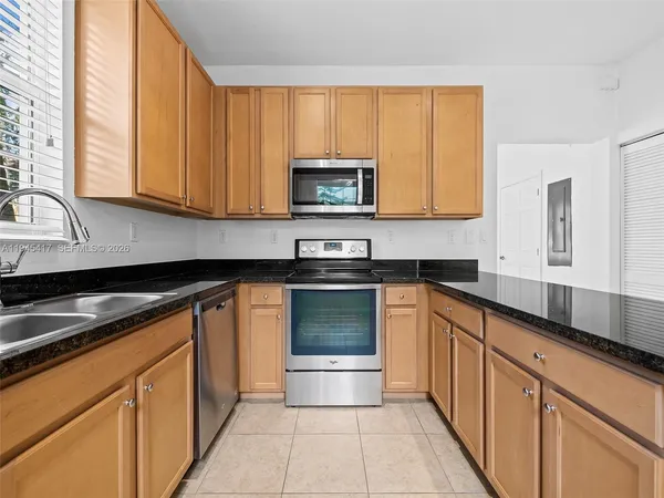 a kitchen with granite countertop a stove sink and cabinets