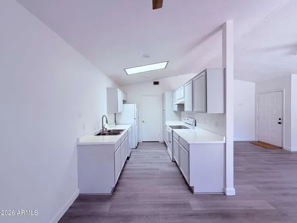 a large white kitchen with sink a refrigerator and white cabinets