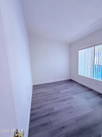 a view of an empty room with wooden floor and fence