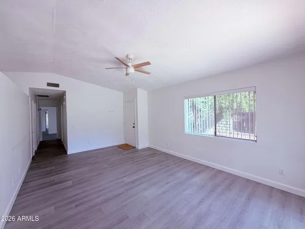 a view of an empty room with a window and wooden floor