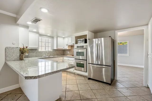 a kitchen with granite countertop a refrigerator and cabinets