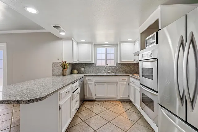 a kitchen with stainless steel appliances granite countertop a refrigerator sink and stove