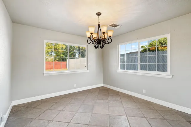 an empty room that has a window and chandelier