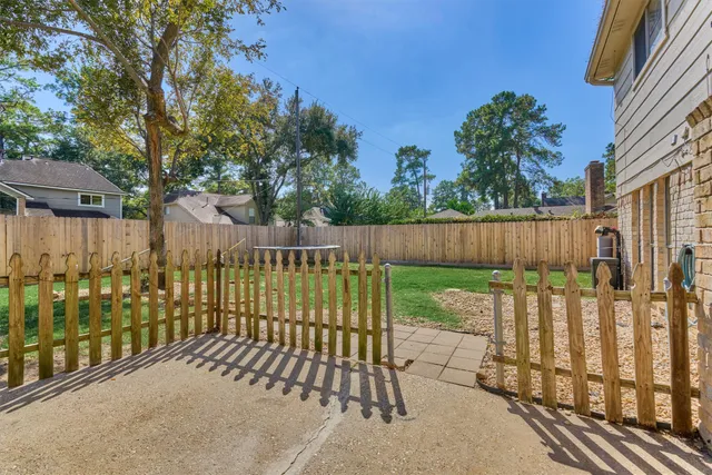 a backyard of a house with lawn chairs and a large tree
