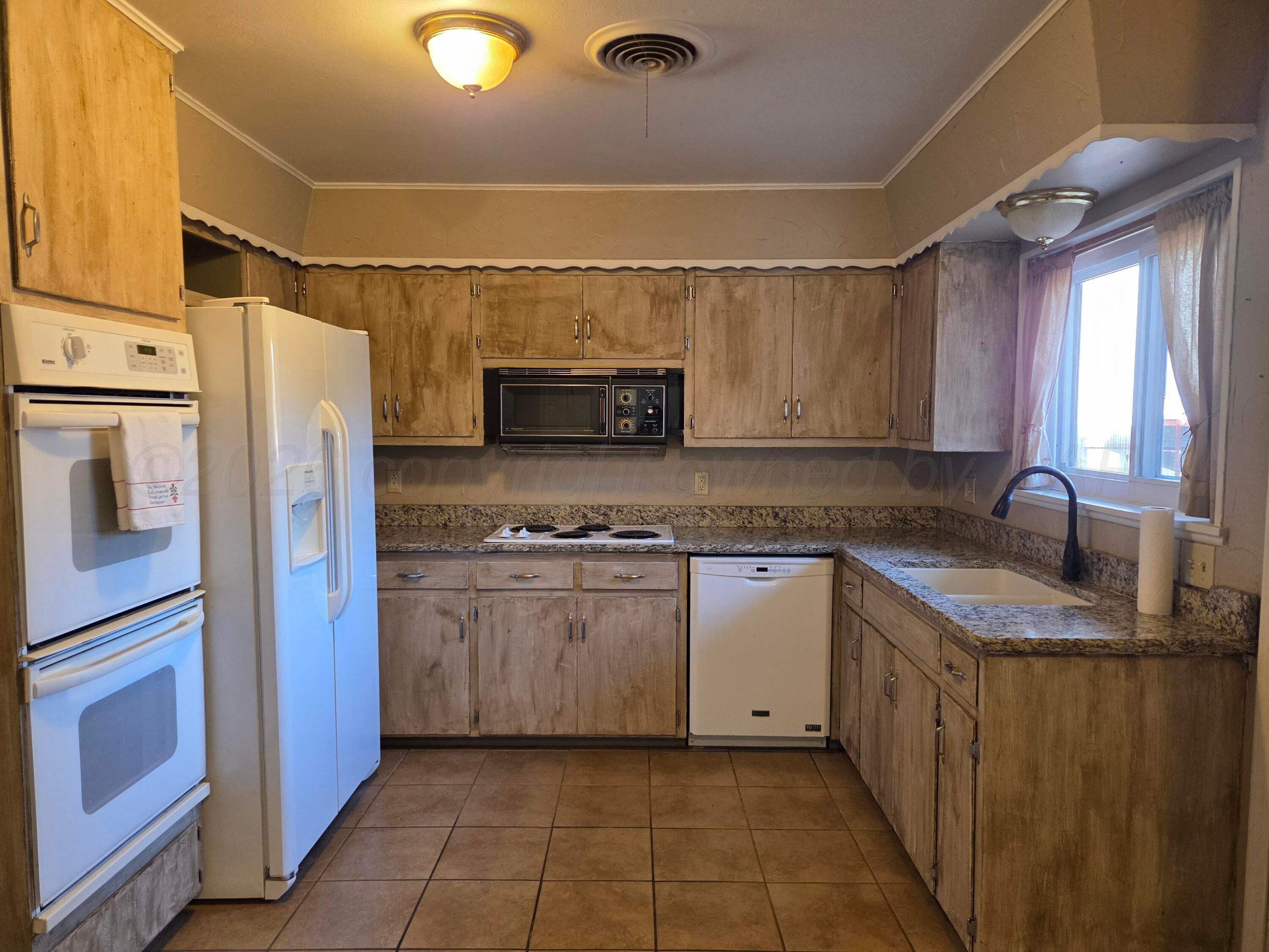 917 South Harvard Street Perryton, TX 79070 - Photo 4 of 30 a kitchen with stainless steel appliances granite countertop a refrigerator sink and stove