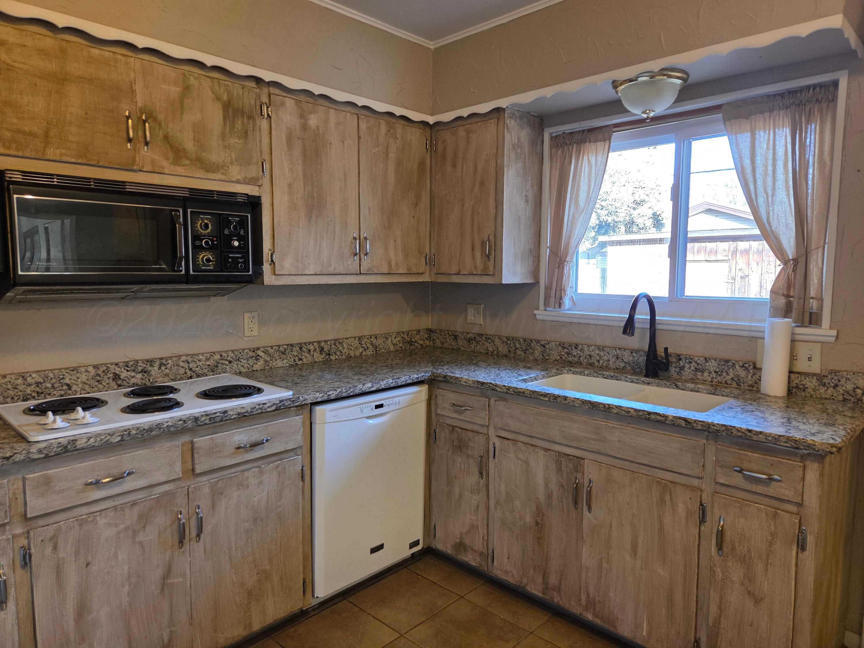 917 South Harvard Street Perryton, TX 79070 - Photo 5 of 30 a kitchen with granite countertop a sink cabinets stainless steel appliances and a window