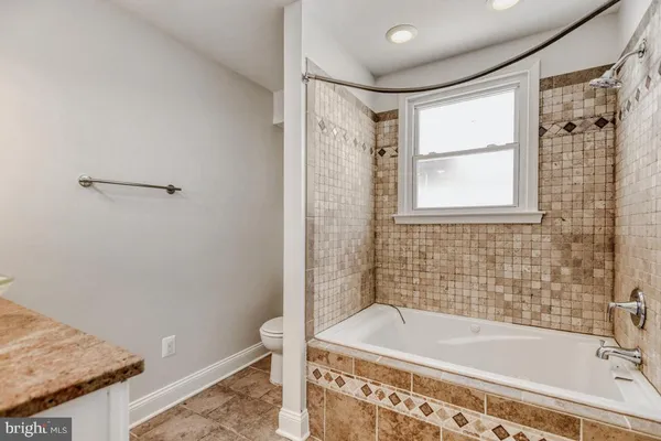 a bathroom with a granite countertop bathtub shower and sink