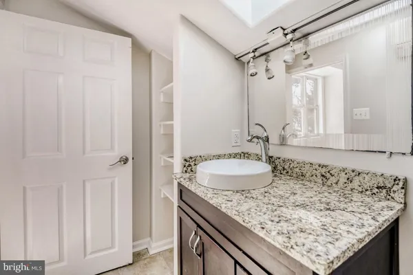 a bathroom with a granite countertop sink and a mirror