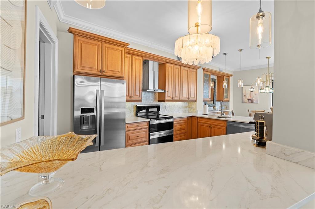 524 La Peninsula Boulevard, Unit 524 Naples, FL 34113 - Photo 17 of 44 a kitchen with stainless steel appliances granite countertop a refrigerator a stove a sink dishwasher and a dining table with wooden floor
