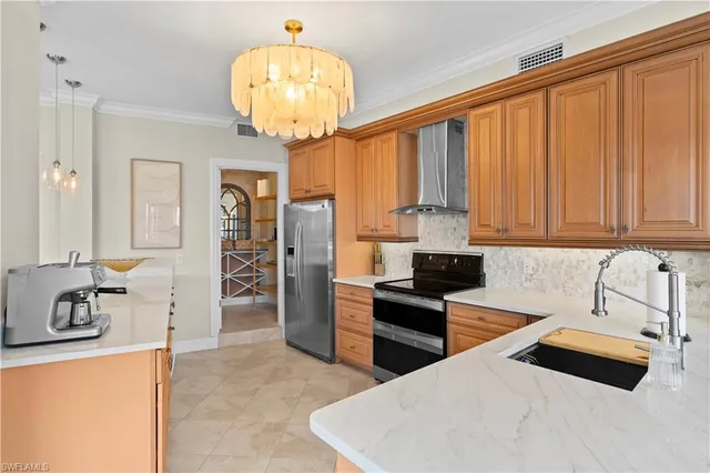 a kitchen with stainless steel appliances a chandelier a refrigerator and a sink