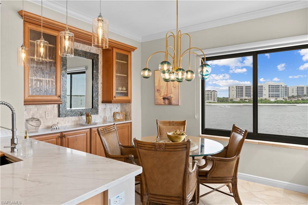 524 La Peninsula Boulevard, Unit 524 Naples, FL 34113 - Photo 23 of 44 a kitchen with a table chairs and wooden floor