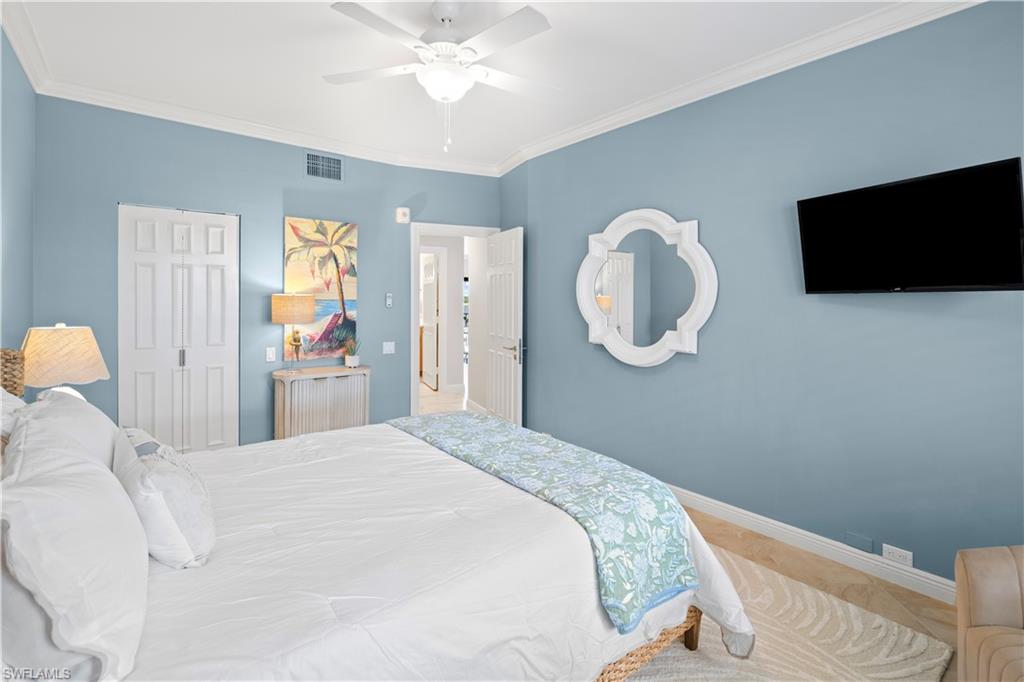 524 La Peninsula Boulevard, Unit 524 Naples, FL 34113 - Photo 39 of 44 a bedroom with a bed and a chandelier