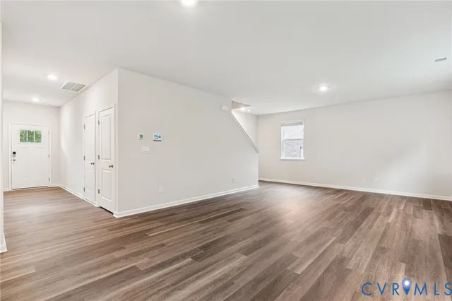 an empty room with wooden floor & windows