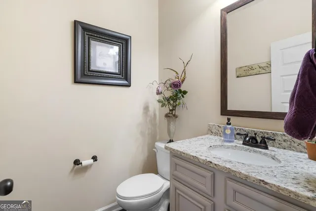 a bathroom with a granite countertop toilet sink and mirror