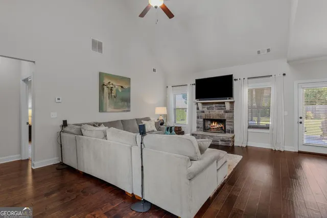 a living room with furniture a fireplace a flat screen tv and wooden floor