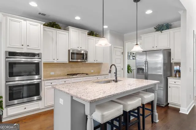 a kitchen with kitchen island a counter space a sink appliances and cabinets