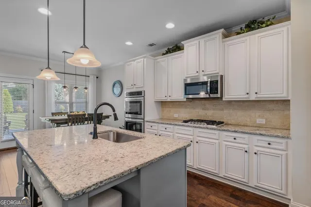 a kitchen with granite countertop white cabinets white stainless steel appliances and chandelier