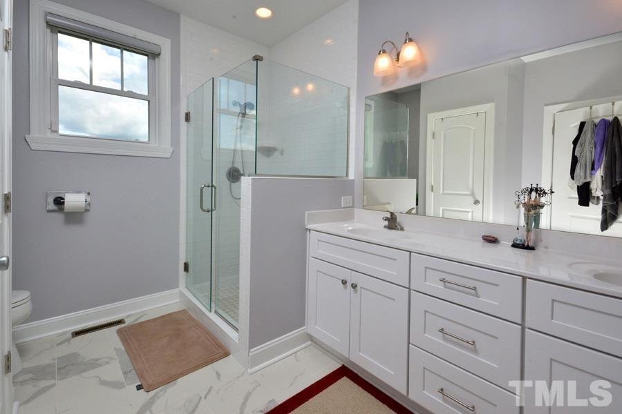 41 South Old Lantern Road Timberlake, NC 27583 - Photo 17 of 25 a bathroom with a double vanity sink a mirror a shower and a bathtub