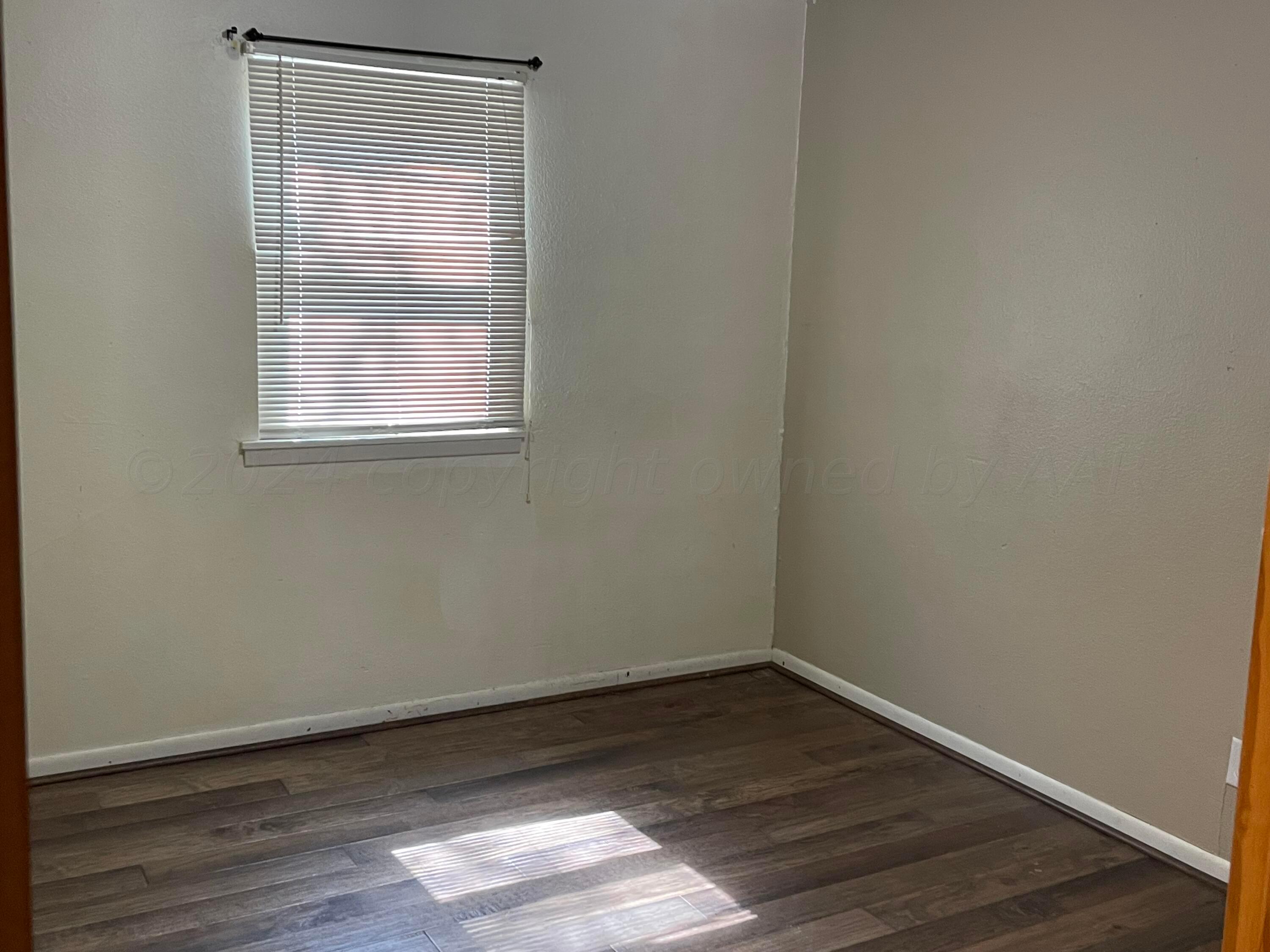 2014 South Drake Street Perryton, TX 79070 - Photo 7 of 10 a view of an empty room with wooden floor and a window