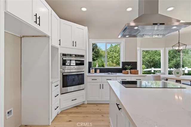a kitchen that has a lot of white cabinets and stainless steel appliances