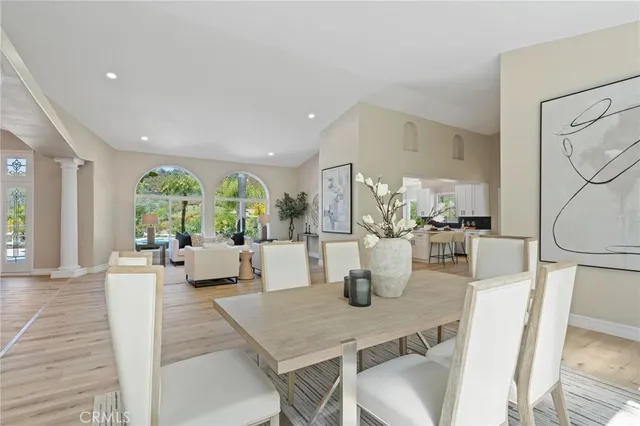 a dining room with wooden floor a chandelier a glass table and chairs