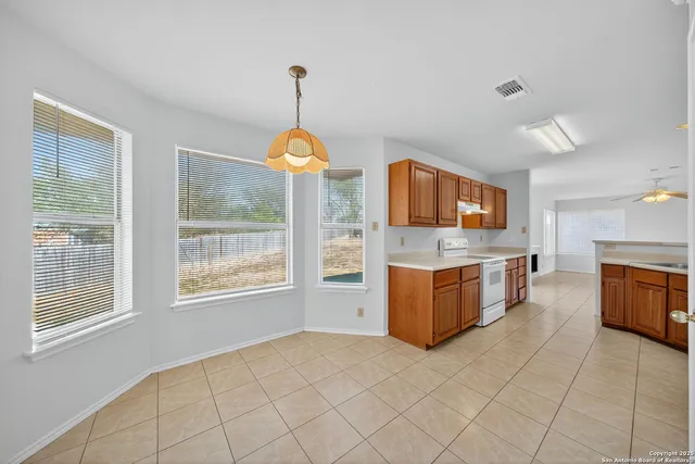a view of a kitchen with stainless steel appliances granite countertop a stove top oven a sink dishwasher a dining table and chair with wooden floor