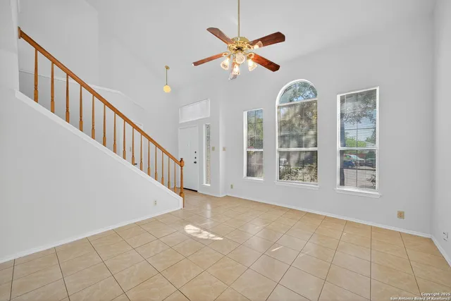 an empty room with wooden floor fan and windows