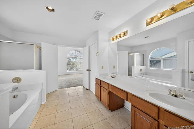 a spacious bathroom with a tub sink and mirror