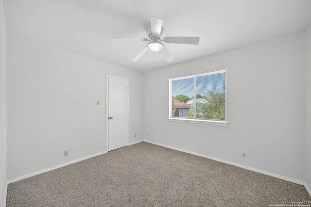 an empty room with a window and a fan