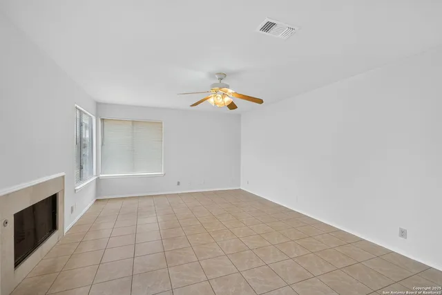 a view of an empty room with chandelier fan and fireplace
