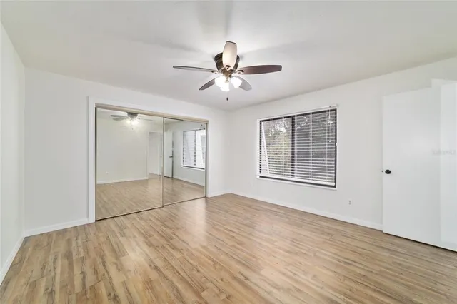 a view of an empty room with chandelier fan and wooden floor