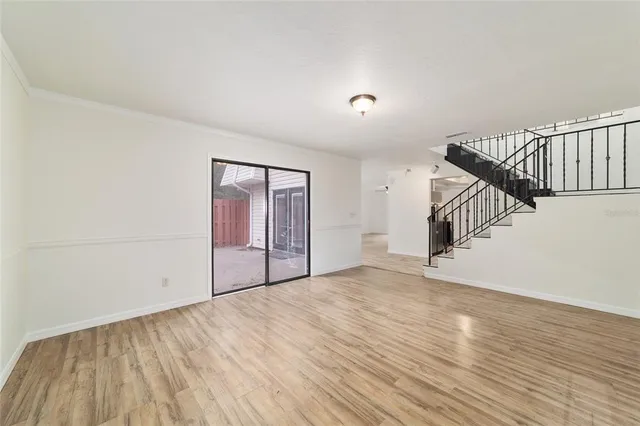 a view of an empty room with wooden floor and stairs