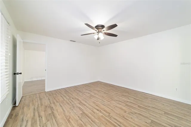 a view of a big room with wooden floor and a chandelier fan