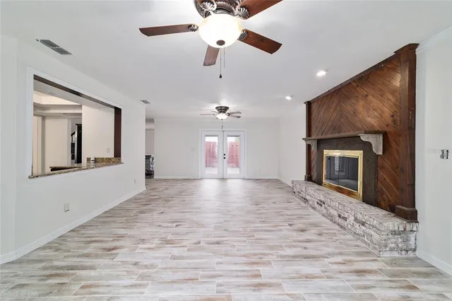 a view of an empty room with a fireplace and a ceiling fan