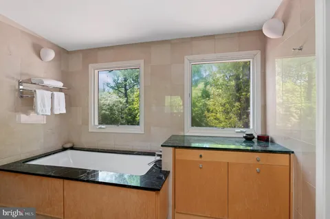 a bathroom with a granite countertop sink and a bathtub