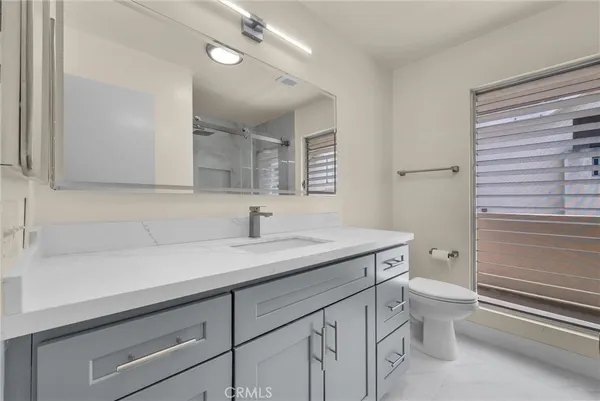 a bathroom with a granite countertop sink a toilet and a mirror