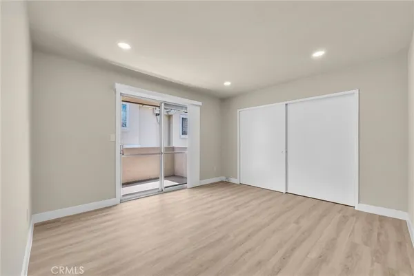 a view of an empty room with wooden floor and closet