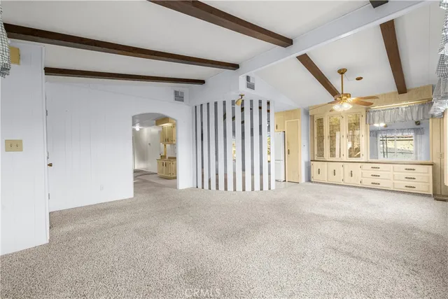 a large room with window ceiling fan and wooden floor