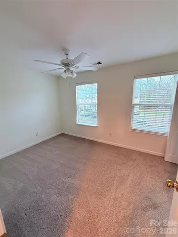 an empty room with windows and fan