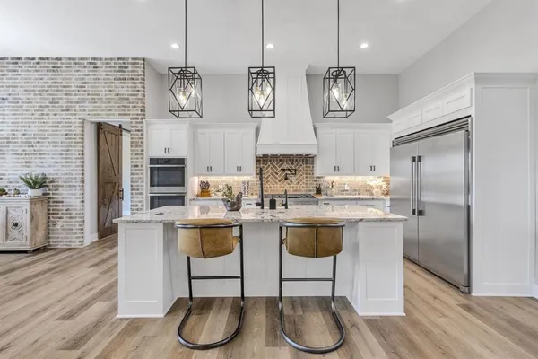 a kitchen with stainless steel appliances granite countertop a kitchen island a stove a refrigerator a sink and a hard wood floors