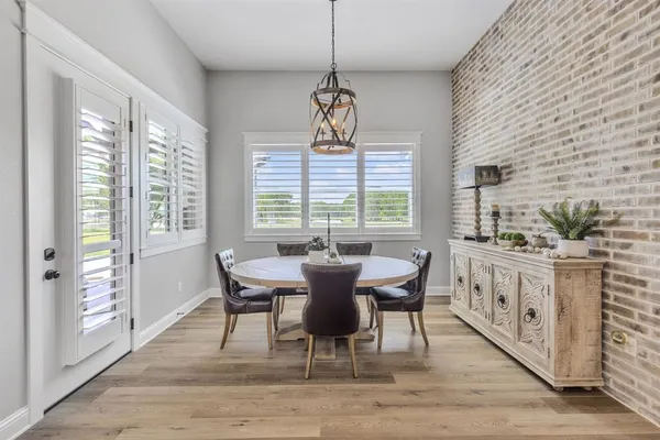 a dining room with wooden floor a chandelier a wooden table and chairs